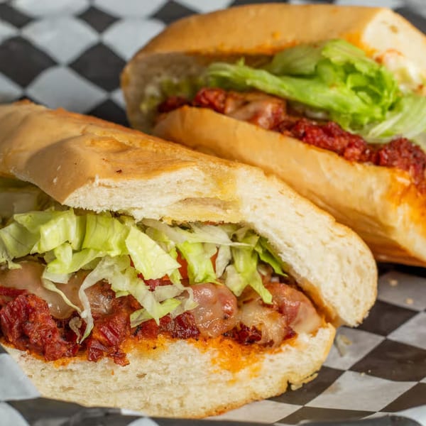 Two Moyitos Cafe & Grill Mexican sandwiches with meat, cheese, and lettuce on checkered paper.