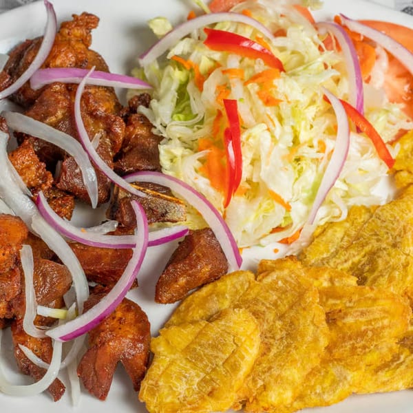 Moyitos Cafe & Grill's fried pork chunks with onions, a fresh salad, and crispy plantains.
