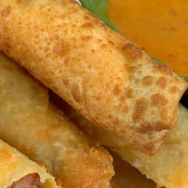 Close-up of golden-brown fried Moyitos Cafe & Grill taquitos with a side of orange dipping sauce.